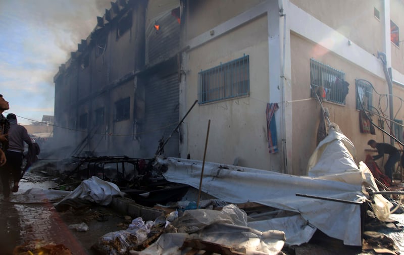 Palestinians try to extinguish a fire at a building of a UNRWA vocational training centre which displaced people use as a shelter (AP Photo/Ramez Habboub)