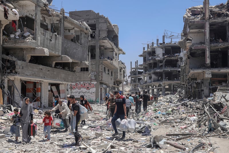 Palestinians walk through the destruction in the wake of an Israeli air and ground offensive in Jebaliya, northern Gaza Strip, in May (Enas Rami/AP)