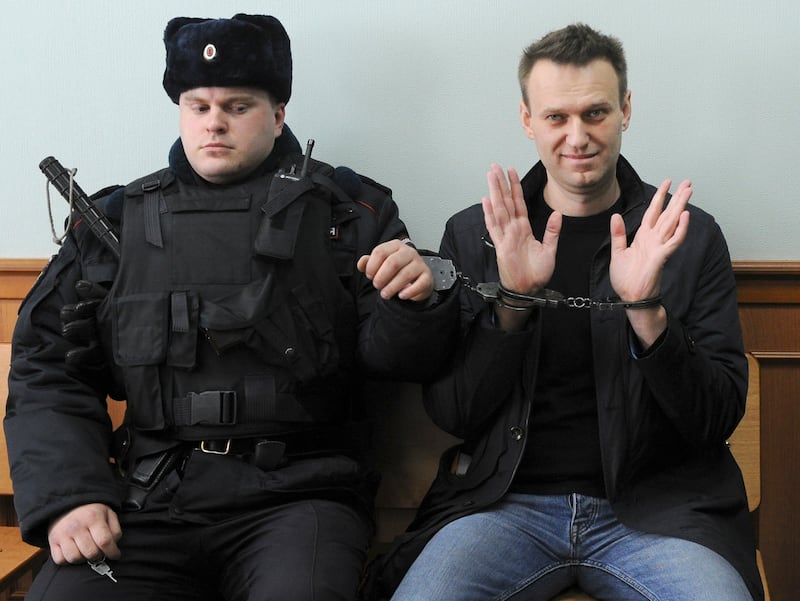 Alexei Navalny, right, poses for press as he sits handcuffed in court in Moscow in 2017 (AP Photo, File)