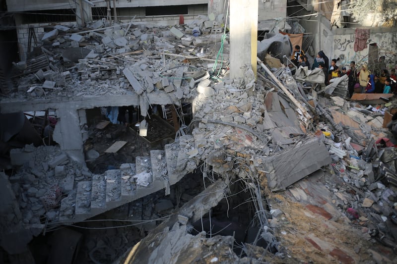 Palestinians look at the destruction after an Israeli strike in Rafah, Gaza Strip (Hatem Ali/ AP)