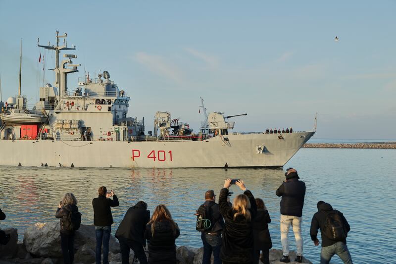 People take photos as the Italian navy ship approaches the port of Shengjin in north-western Albania (Vlasov Sulaj/AP)