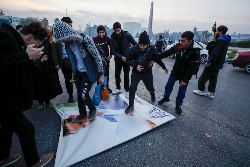 Syrians celebrate the arrival of opposition fighters as they step on a picture of Syrian President Bashar Assad in Damascus (Omar Sanadiki/AP)