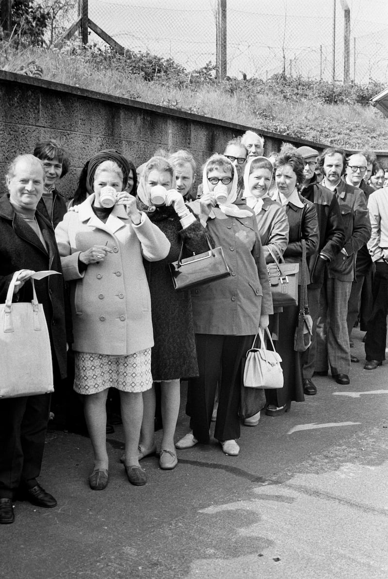 People queuing for for unemployment and social security benefits in the Belfast suburb of Newtownbreda keep their spirits up with a cup of tea