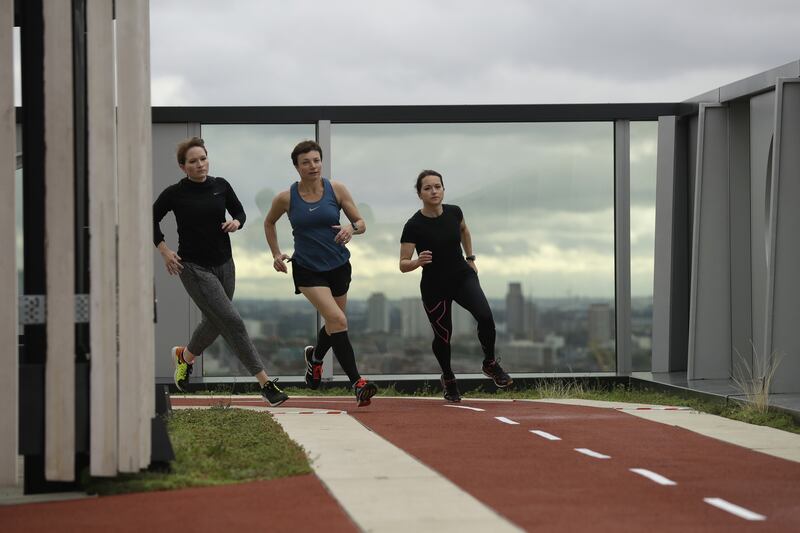 Volunteers run along a running track on top of a building in London