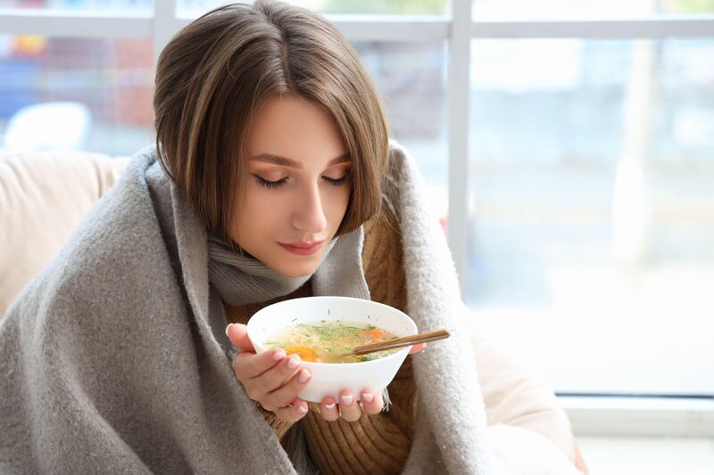 Ill young woman eating chicken soup at home