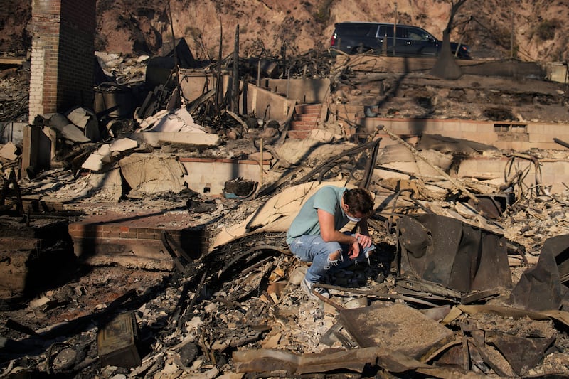 Luke Dexter kneels as he sifts through the remains of his father’s fire-ravaged beachfront property in the aftermath of the Palisades Fire (John Locher/AP)