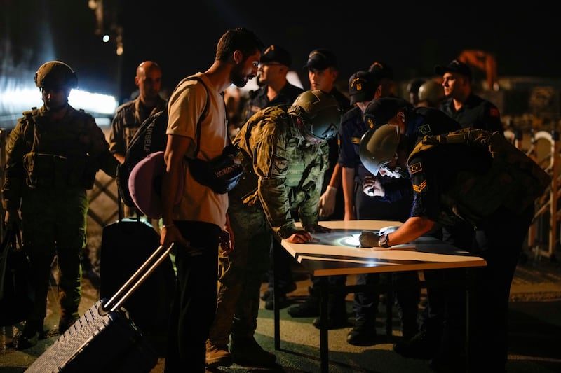 Turkish security officials verify the travel documents of citizens before boarding Turkish military ships to evacuate them from Lebanon to Turkey in Beirut port (Emrah Gurel/AP)