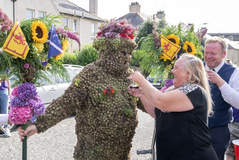 The Burryman gets a nip of whisky using a straw from resident Yvonne Martin