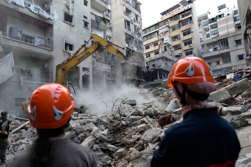 Rescue workers use an excavator to clear the rubble of destroyed buildings as they search for victims of an Israeli airstrike in Beirut (AP Photo/Hussein Malla)