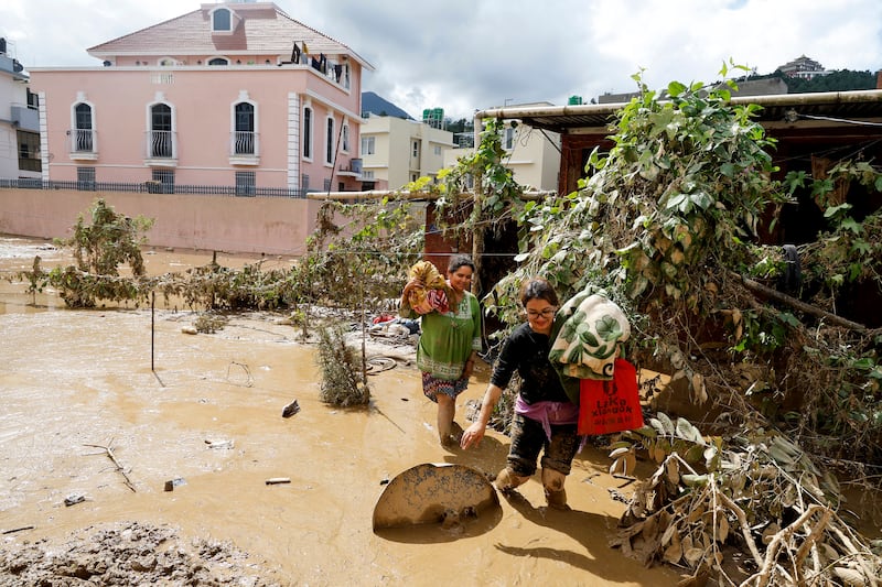 Women walk with their belongings in Kathmandu in the aftermath of the disaster (Gopen Rai/AP)