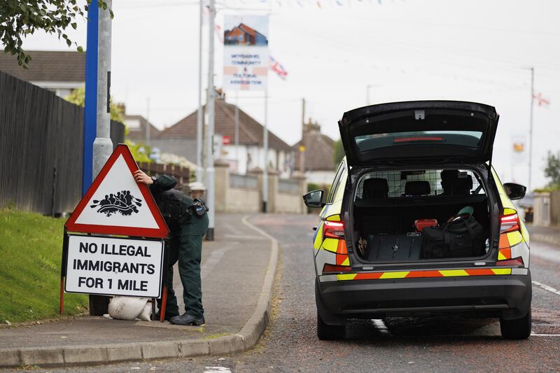 PSNI officer on Monday removing a road sign with image of people a dingy boat with the message, ‘No illegal immigrants for 1 mile’, erected close to the Orange Arch in Moygashel, Co Tyrone