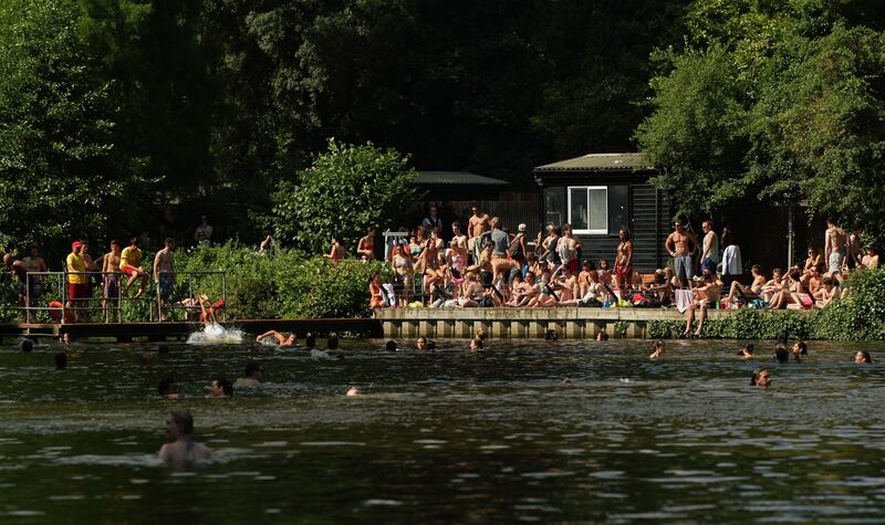 People flock to Hampstead Heath ponds in London to cool down from the heat