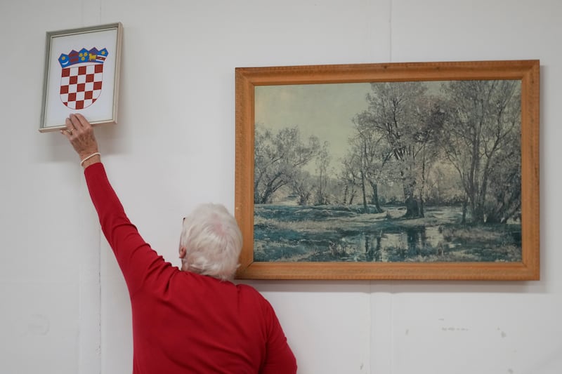 A member of the election commission sets the coat of arms at a polling station in Zagreb (Darko Bandic/AP)