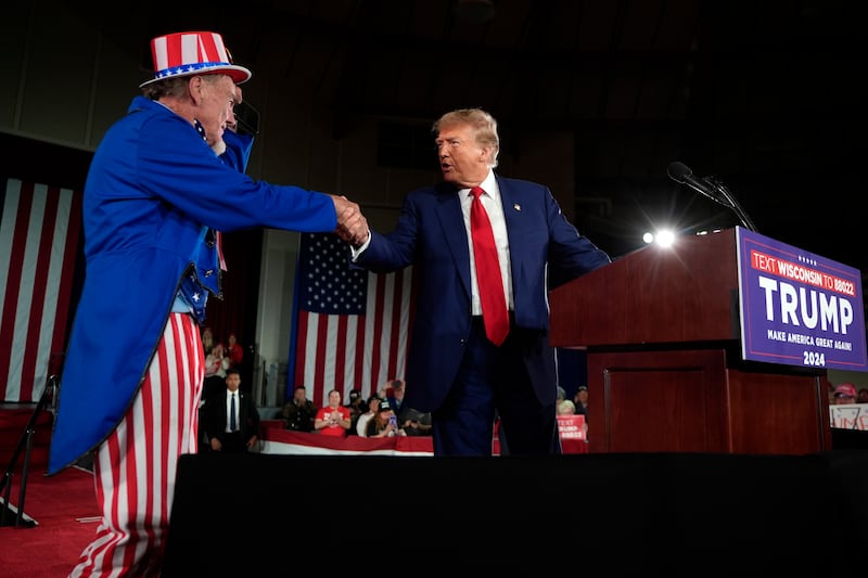 Donald Trump shakes hands with a man dressed as Uncle Sam at the campaign rally (Morry Gash/AP)