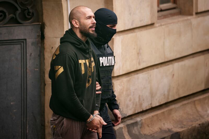 A police officer escorts Andrew Tate from the Court of Appeal in Bucharest (Andreea Alexandru/AP)