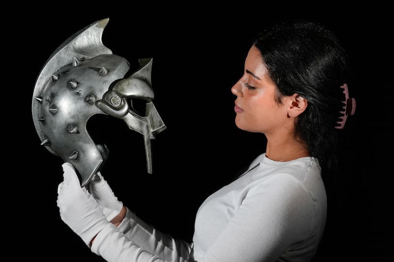 A Propstore employee holds Maximus’ (Russell Crowe) arena helmet and mask