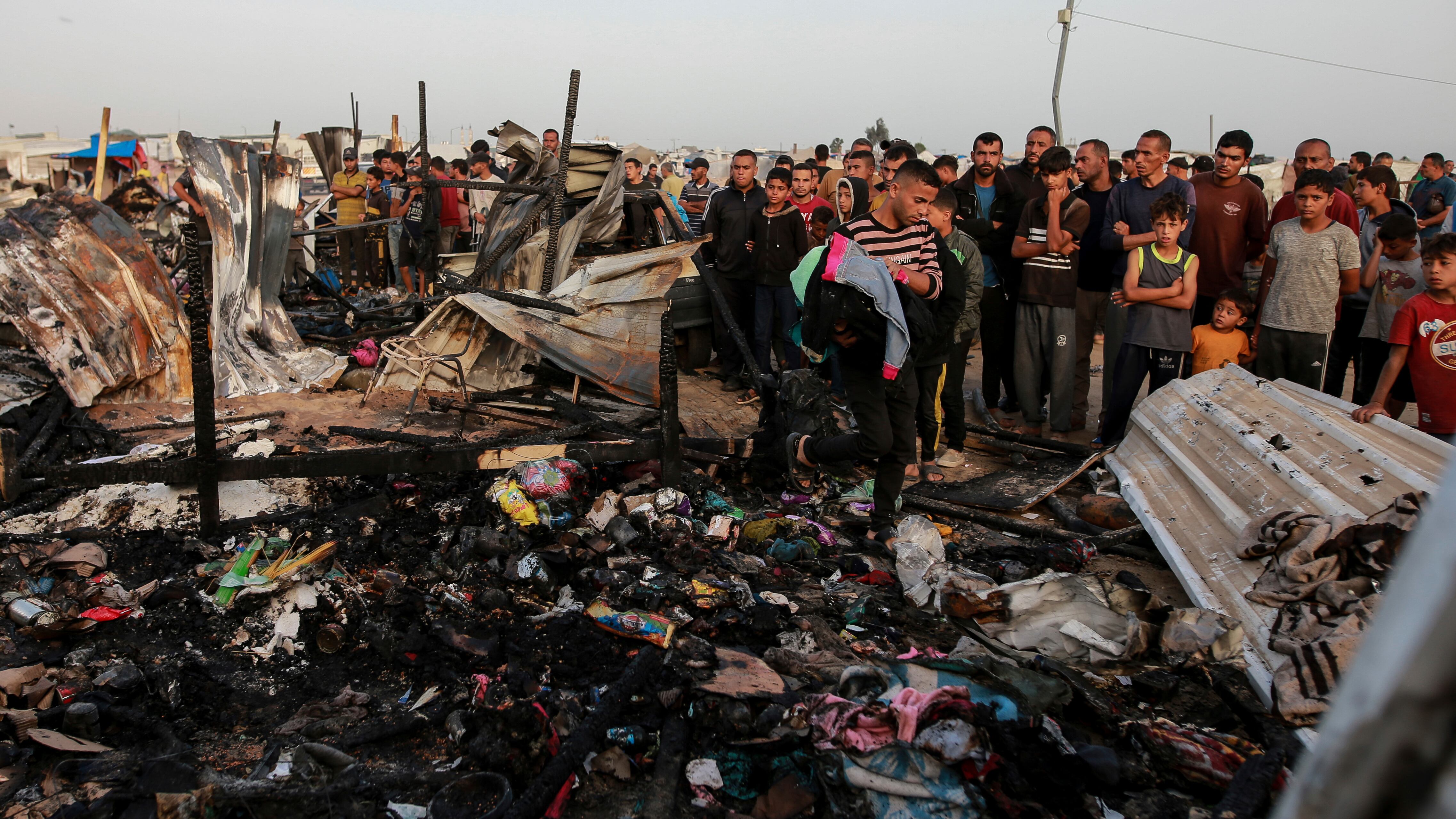 Palestinians look at the destruction after an Israeli strike where displaced people were staying in Rafah