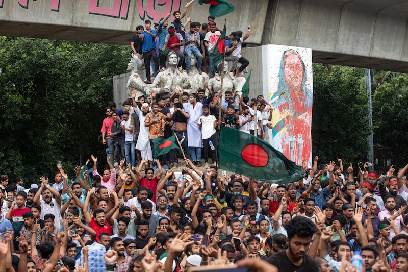 Protesters climb a public monument as they celebrate the news of Prime Minister Sheikh Hasina’s resignation, in Dhaka (Rajib Dhar/AP)