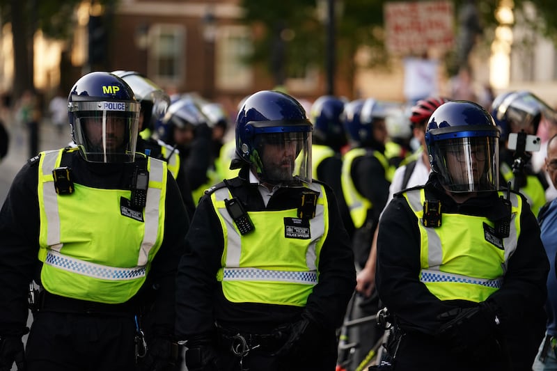 Police officers look on as people attend a protest in Whitehall, London in July