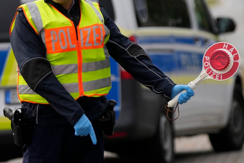 A police officer stops cars and trucks at a border crossing point between Germany and Czech Republic (Matthias Schrader/AP)