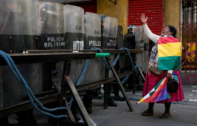 Police block a road to the presidential palace as a supporter of former president Evo Morales shouts during an anti-government protest in La Paz (Juan Karita/AP)