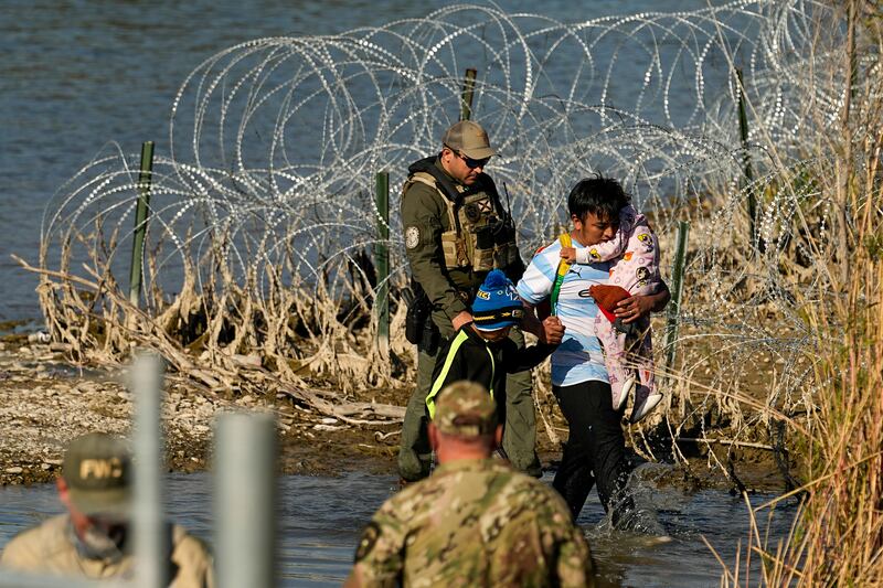 Migrants are taken into custody by officials at the Texas-Mexico border