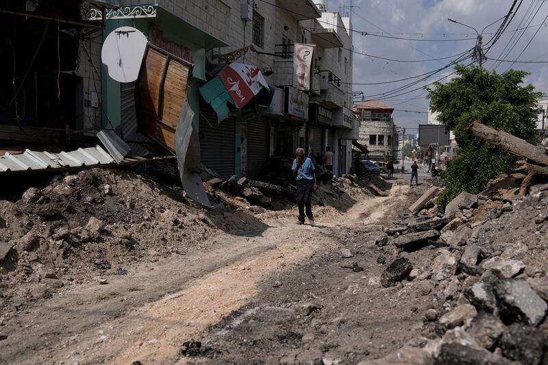 A Palestinian man walks on a street damaged during a military operation in the West Bank city of Jenin (Majdi Mohammed/AP)