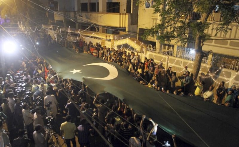 Pakistani cricket fans wave a huge national flag as they gather to welcome skipper Sarfraz Ahmed 