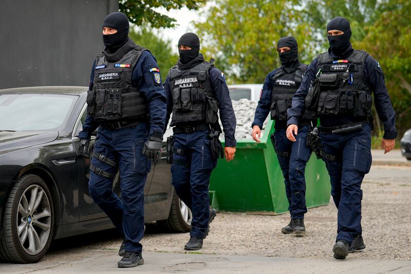 Gendarmes wearing balaclavas walk outside the residence of Andrew Tate during an early morning police search raid on the outskirts of Bucharest, Romania (Vadim Ghirda/AP)