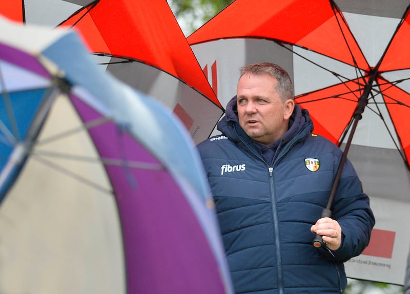 A man wearing an Antrim jacket and holding an umbrella