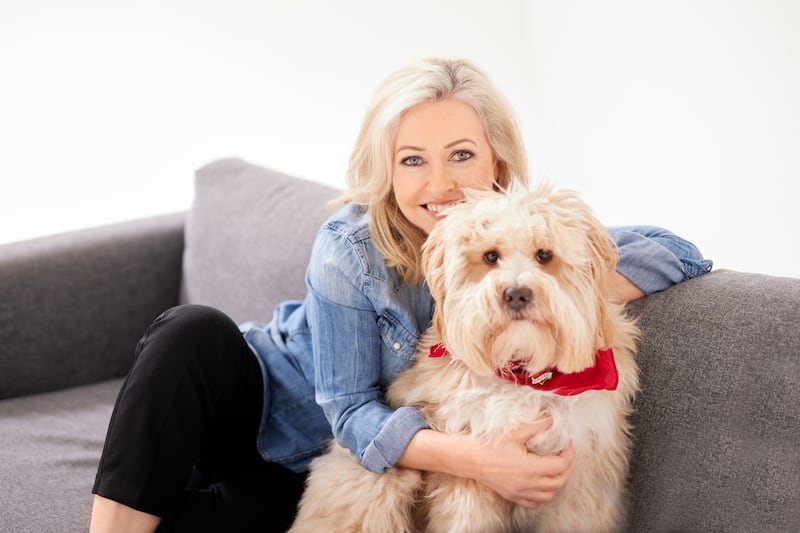 Cathy Kelly hugging a dog on a sofa