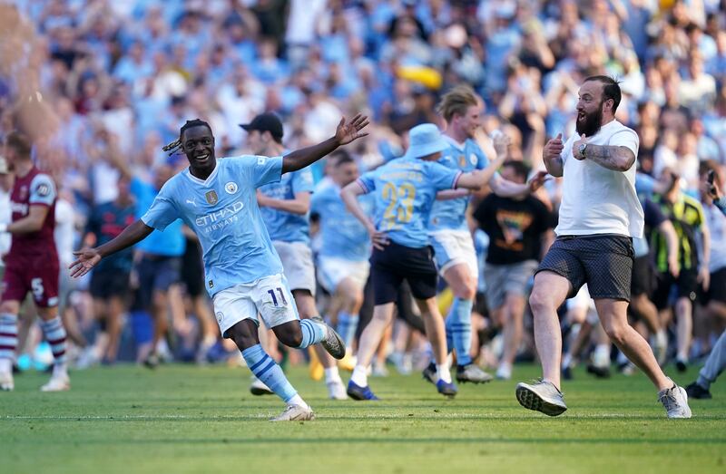 Jeremy Doku celebrates as fans invade the pitch following City’s title success