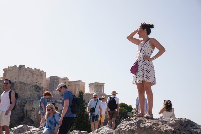 Tourists stand on a hill in front of the Acropolis in central Athens (Petros Giannakouris/AP)