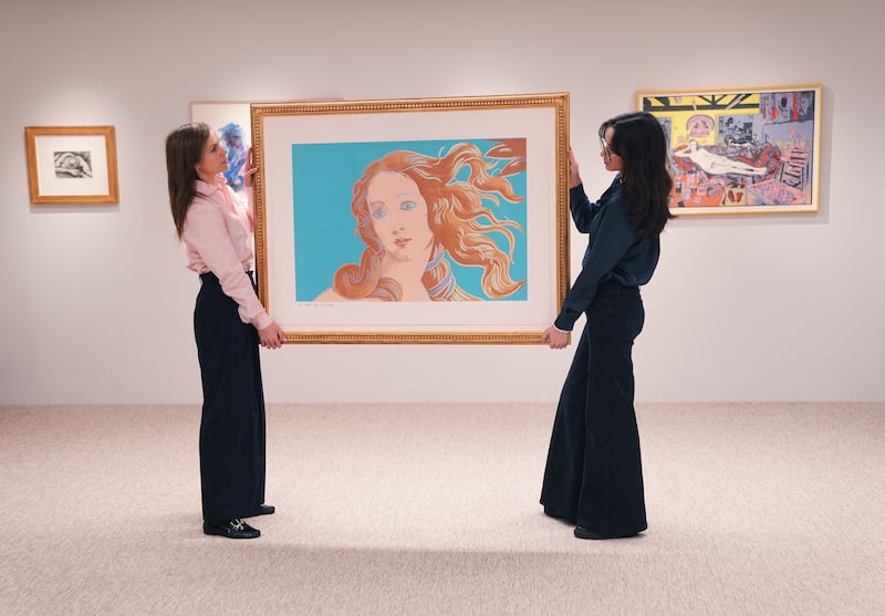 Gallery staff holding a piece by Andy Warhol