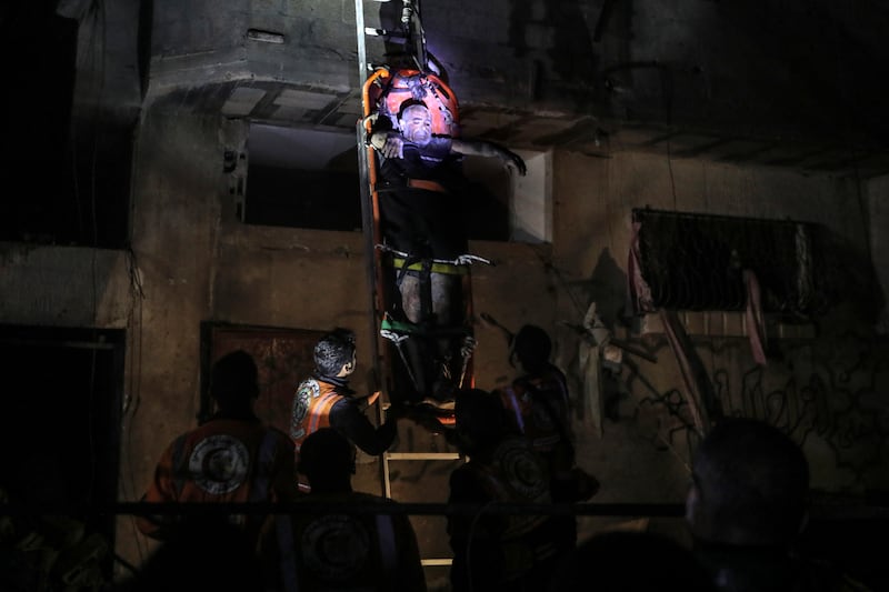 Palestinian civil defence members evacuate survivors of the Israeli bombardment on a residential building of Abu Alenan family in Rafah (AP)