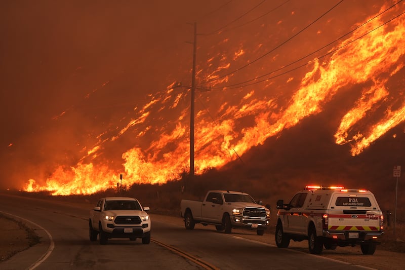 Firefighters monitor flames caused by the Hughes Fire along Castaic Lake in Castaic, California (Marcio Jose Sanchez/AP)