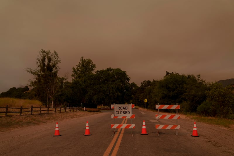 Signs and traffic cones block a road to Sycamore Valley Ranch, formerly the Neverland Ranch when it was owned by Michael Jackson, as firefighters work against the advancing Lake Fire in Los Olivos, California (Eric Thayer/AP)