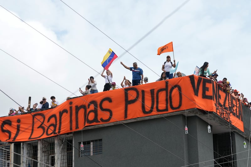 Supporters stand on the roof of a building adorned with a banner with a message that reads Spanish; “If Barinas could, Venezuela can” during a campaign rally for opposition presidential candidate Edmundo Gonzalez in Barinas, Venezuela (Ariana Cubillos/AP)