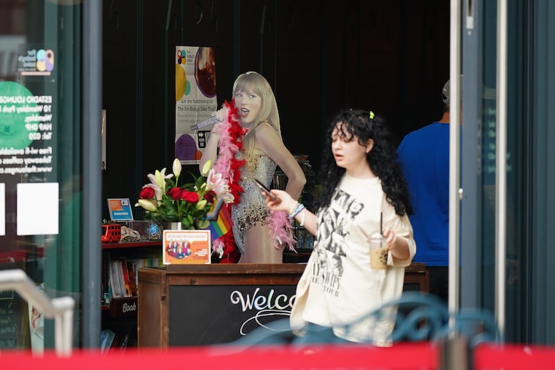 A Swiftie walks past a Taylor Swift cardboard cut-out in a cafe near Wembley Stadium