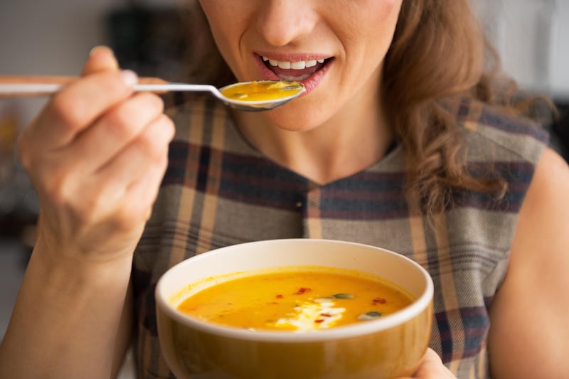 Close up of woman eating some pumpkin soup