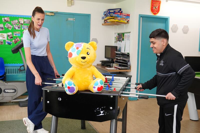 Footballer Jill Scott plays table football during a visit to Community On Solid Ground