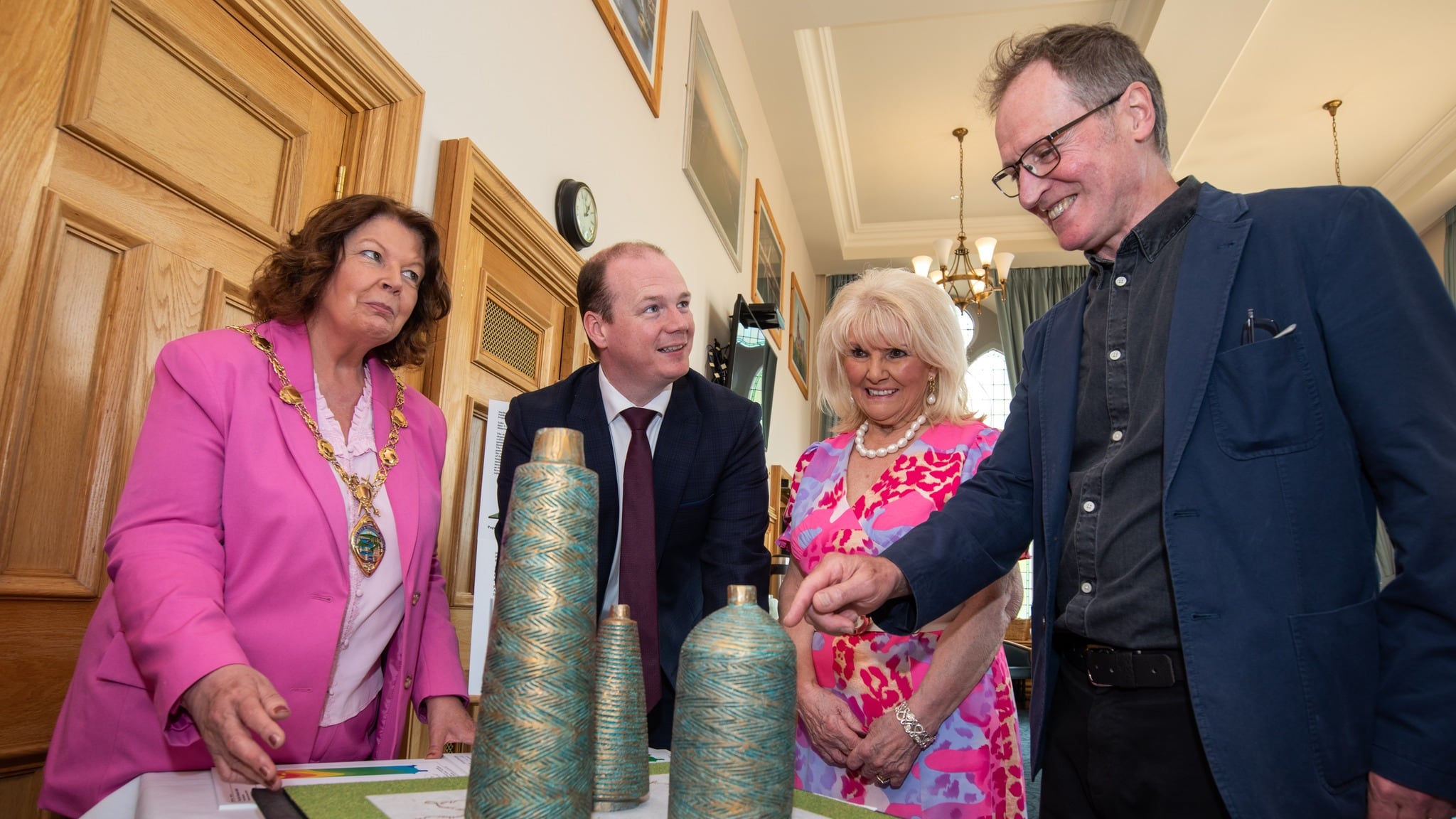 Former Communities Minister Gordon Lyons is pictured with (L-R) former Mayor of Derry City and Strabane District Council, Cllr Patricia Logue, Factory Girls representative Mary White and artist Chris Wilson, with the design of the Factory Girls' artwork.