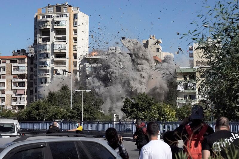 People watch a building collapse after being hit by an Israeli airstrike in Ghobeiri, Beirut (Bilal Hussein/AP)