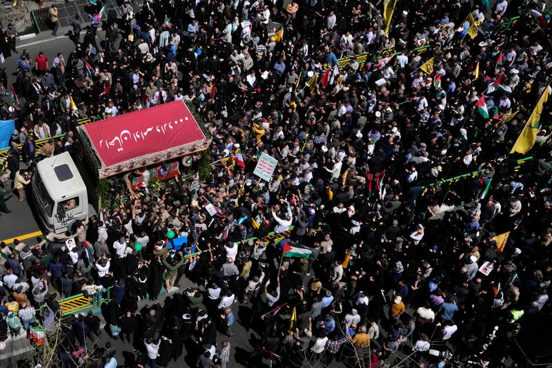 Mourners gather around a lorry carrying the flag-draped coffins of Revolutionary Guard members (Vahid Salemi/AP)