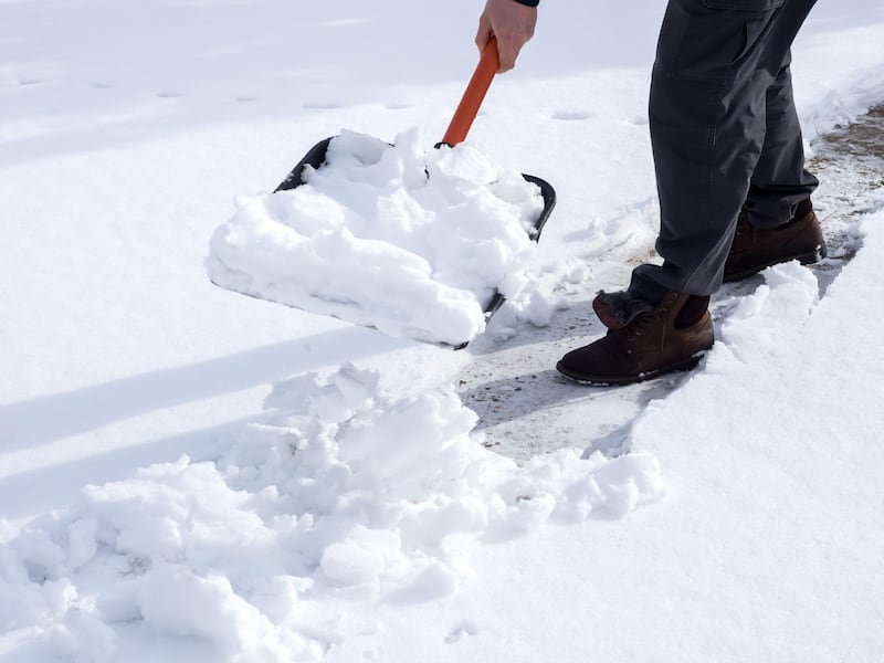 Close up image of a man shovelling snow in a garden