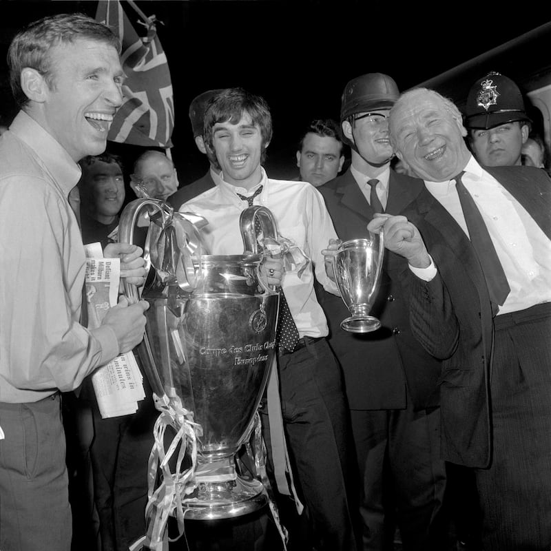 (L-R) Manchester United's Pat Crerand, George Best and manager Matt Busby celebrate with the European Cup, the day after their 4-1 win over Benfica