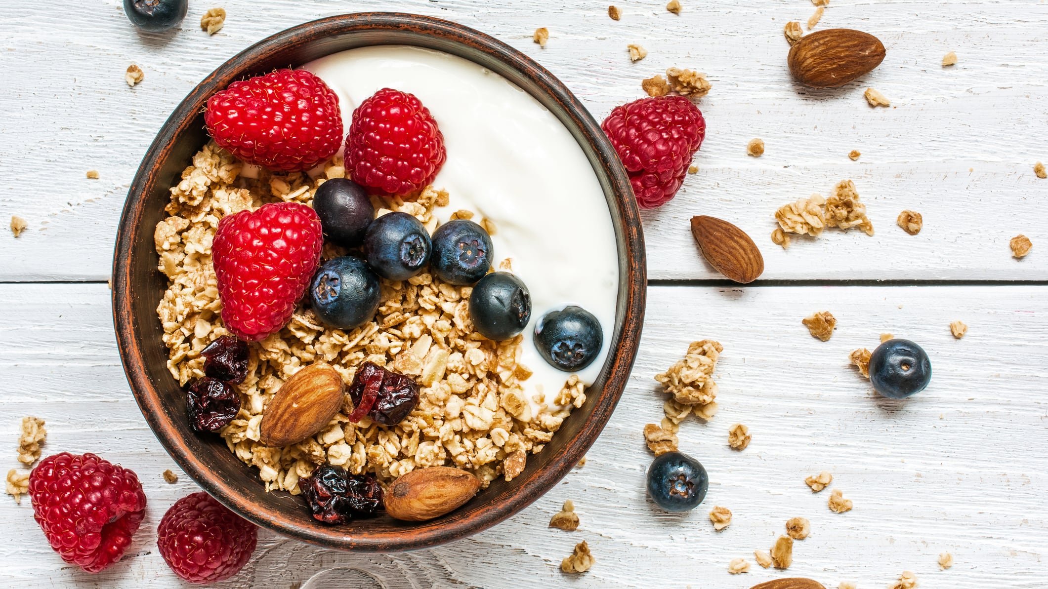 bowl of oat granola with yogurt, fresh raspberries, blueberries
