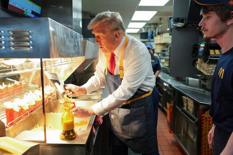 Donald Trump serves fries as an employee watches (Doug Mills/The New York Times/AP/Pool)