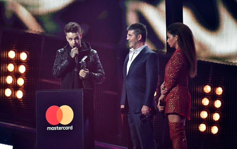 Nicole Scherzinger and Simon Cowell look on as Liam Payne collects his award for One Direction on stage at the Brit Awards