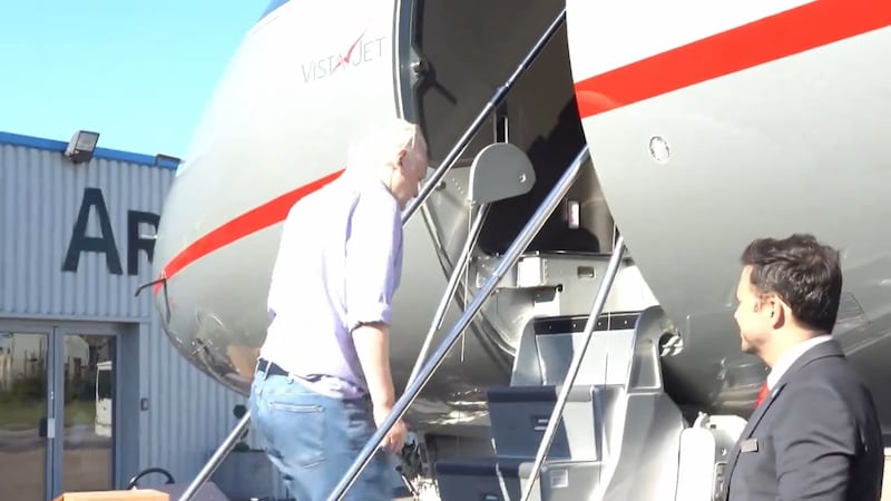 Julian Assange boards a plane to leave the UK